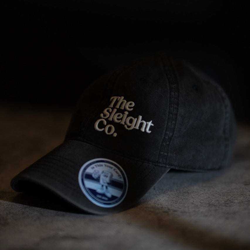 Dark gray cap with 'The Sleight Co.' logo on a textured surface